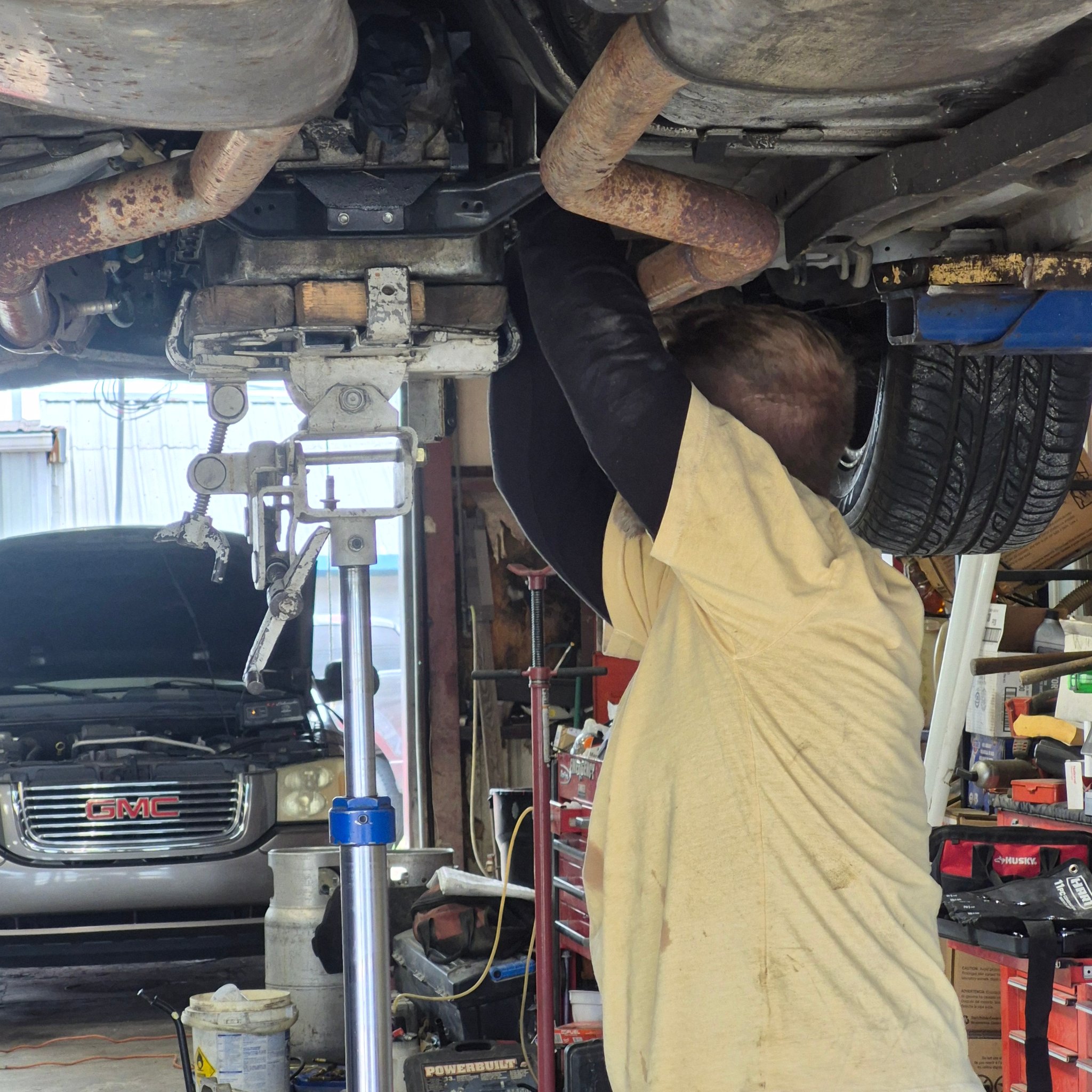Mechanic working under a vehicle on a lift at Expert Collision LLC